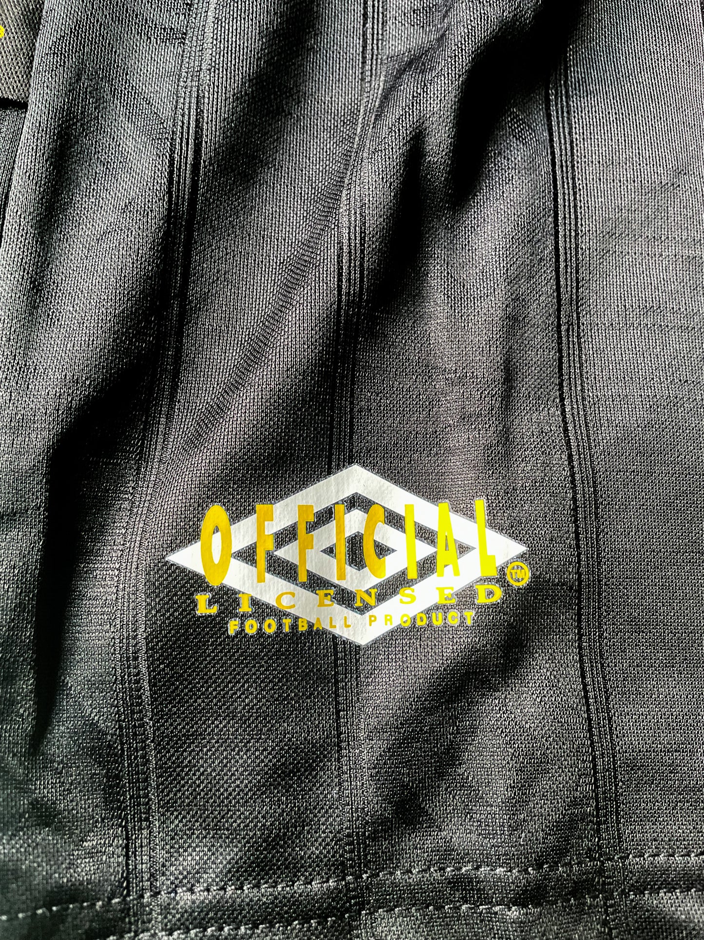 Close-up of Umbro logo, club crest, and fold-over collar