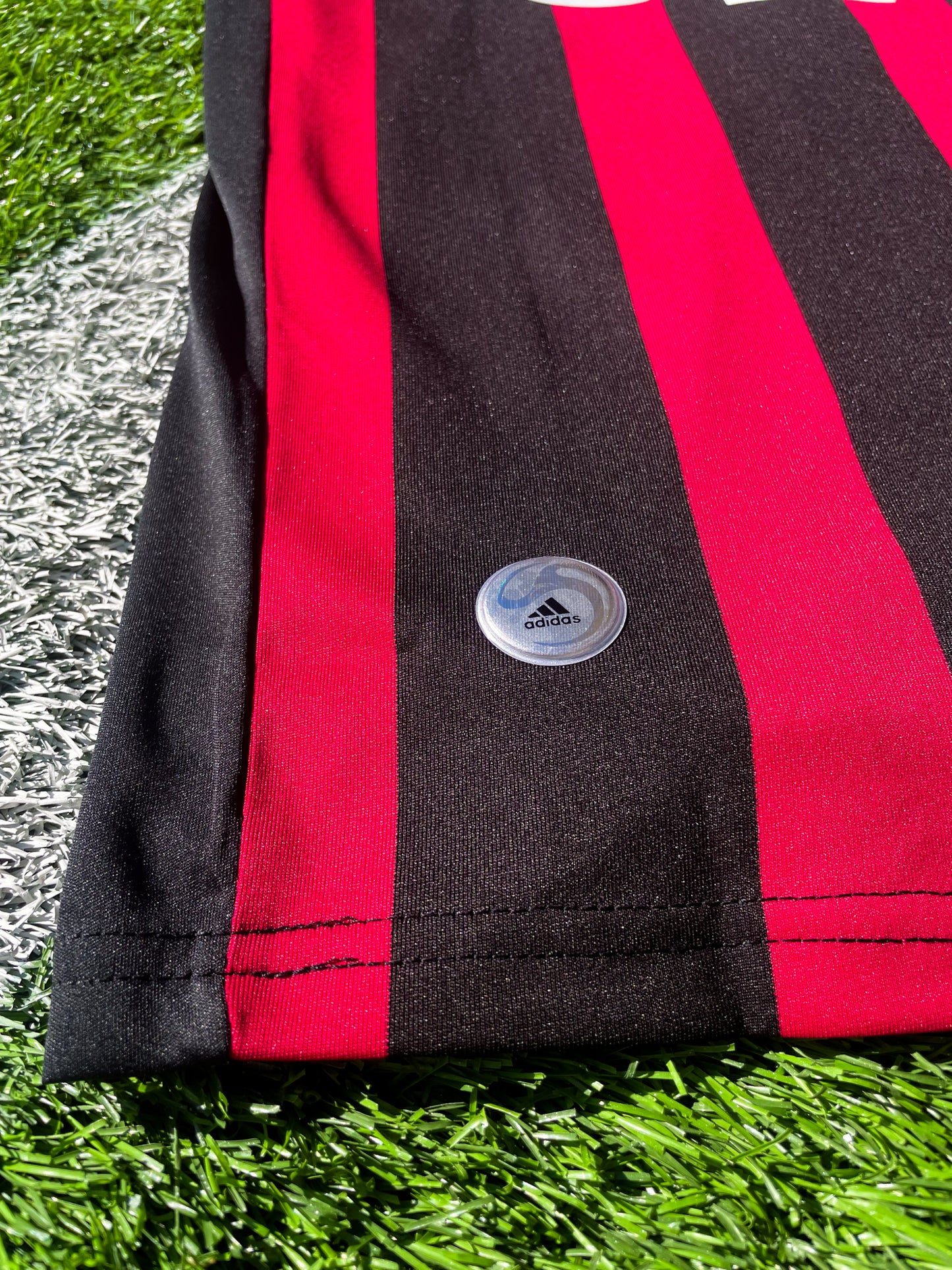 Close-up of Adidas logo and AC Milan crest on the 2009-2010 home jersey