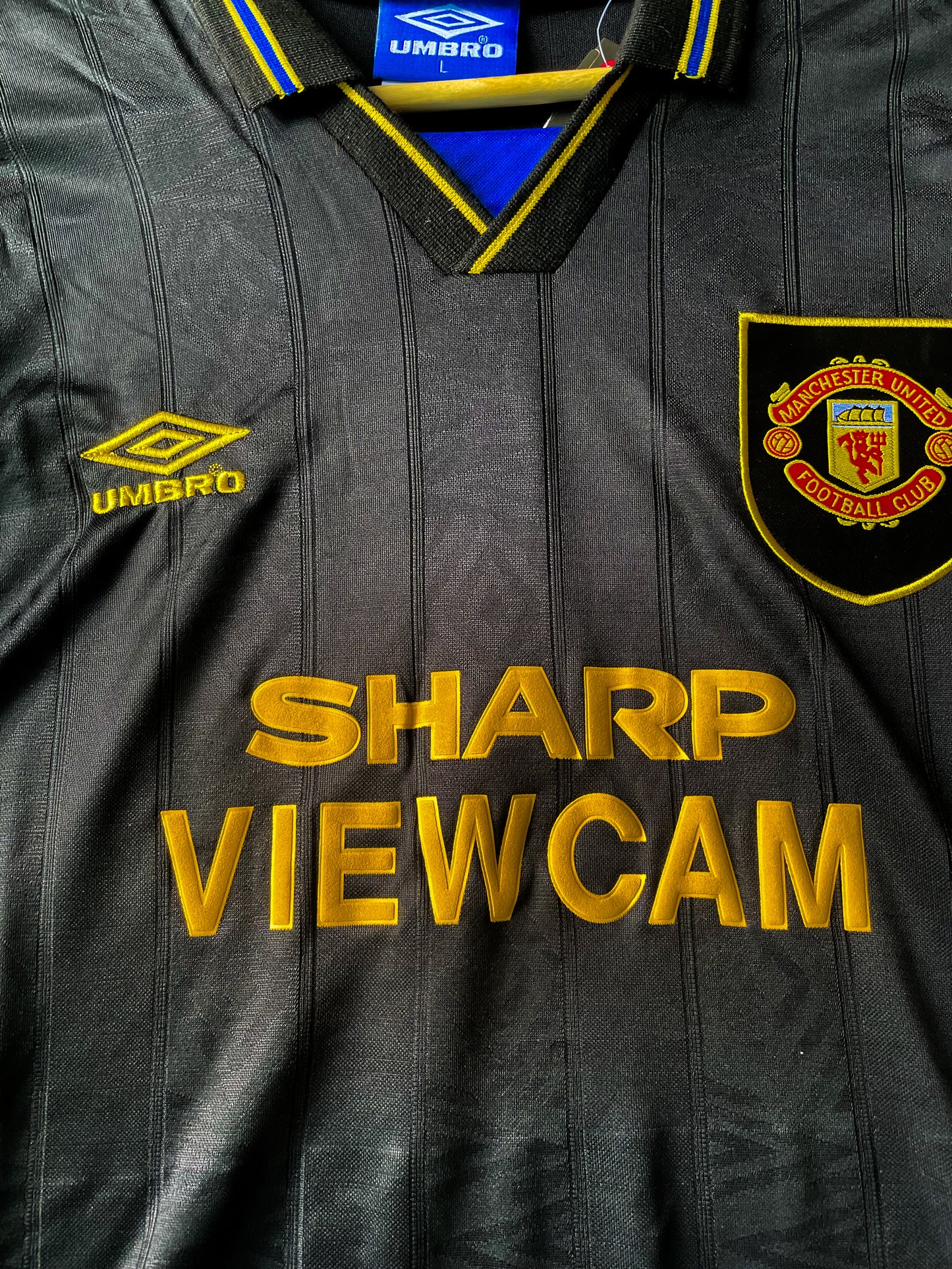 Close-up of Umbro logo, club crest, and fold-over collar