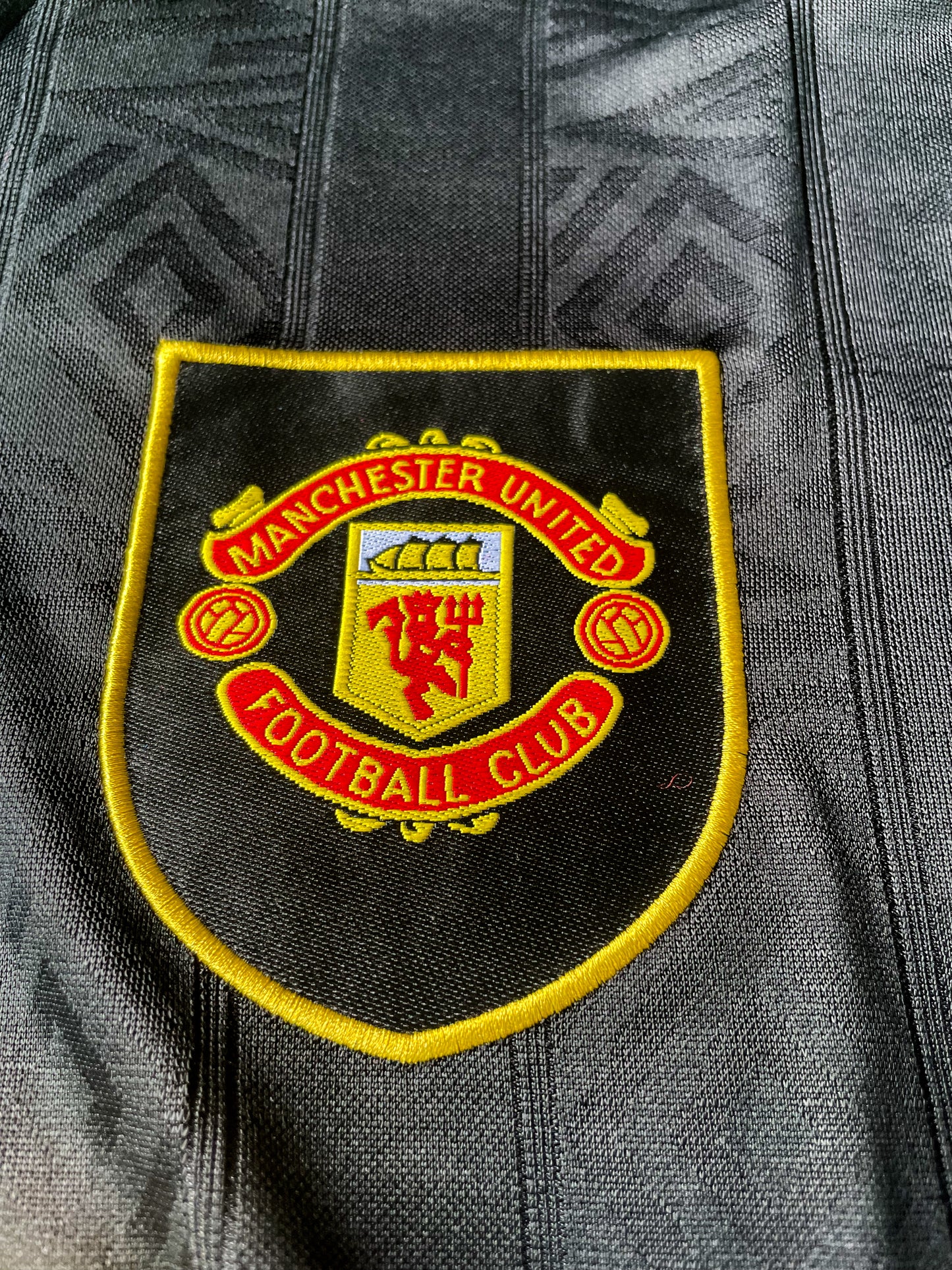 Close-up of Umbro logo, club crest, and fold-over collar