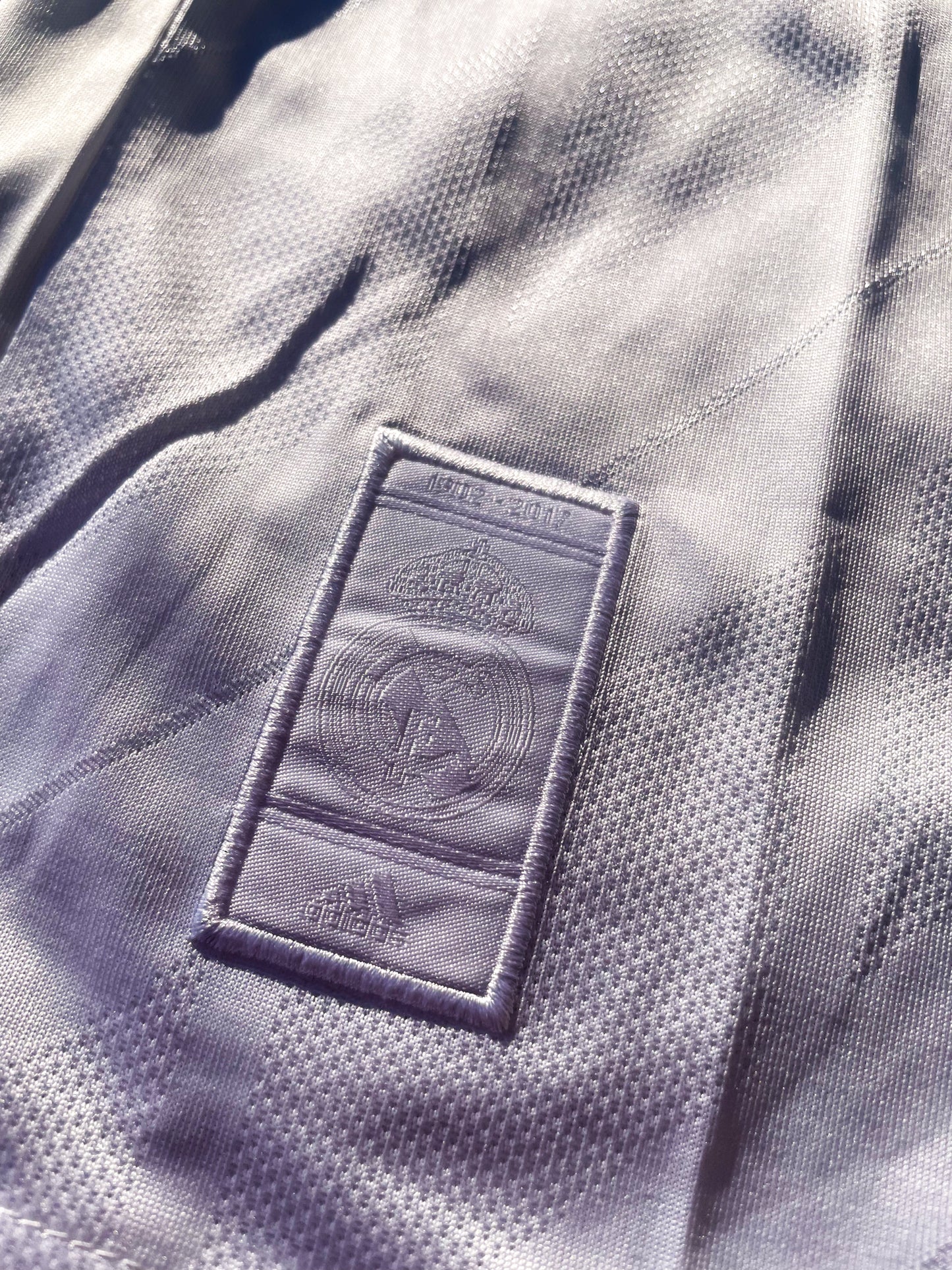 Close-up of embroidered club crest and Nike swoosh on white fabric