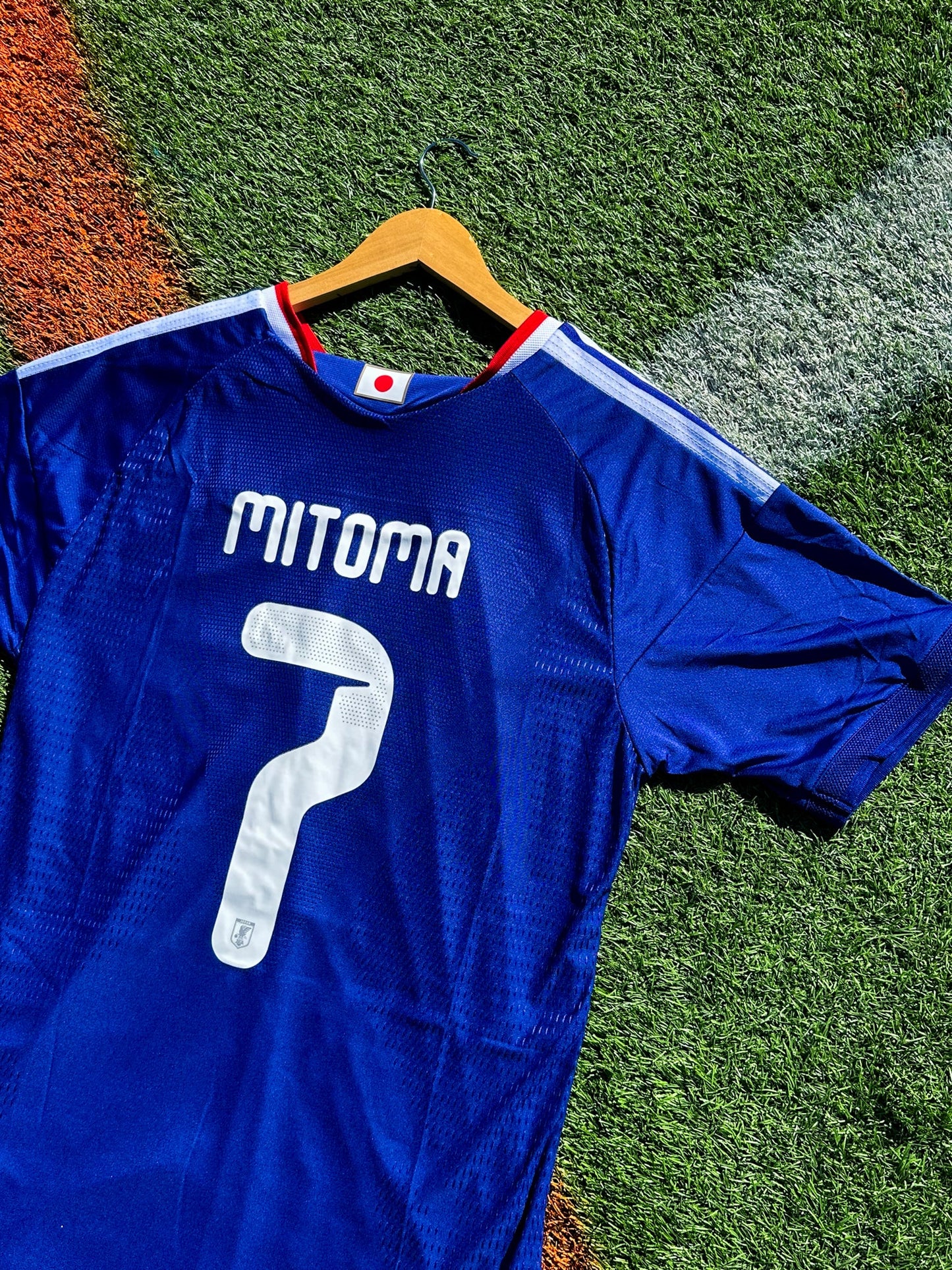 Blue sports jersey with 'Mitona' branding on grass