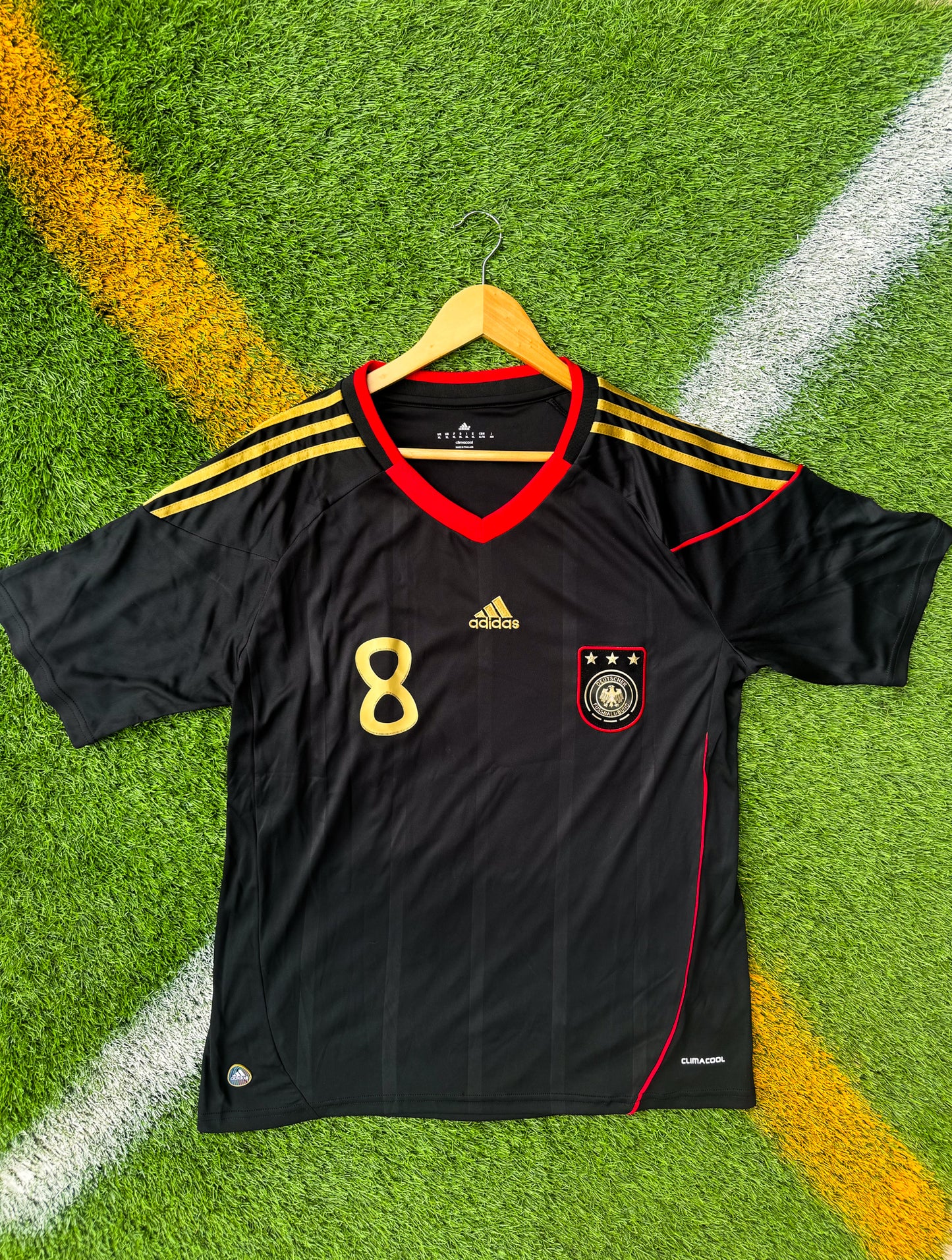 Front view of Germany 2010 away jersey with black base and red/gold details

