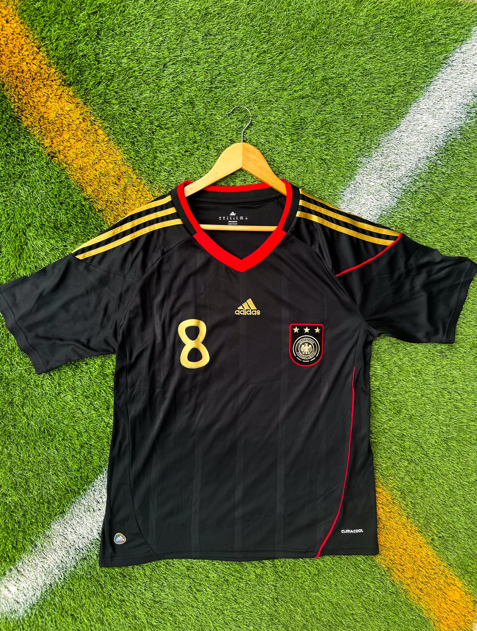 Front view of Germany 2010 away jersey with black base and red/gold details

