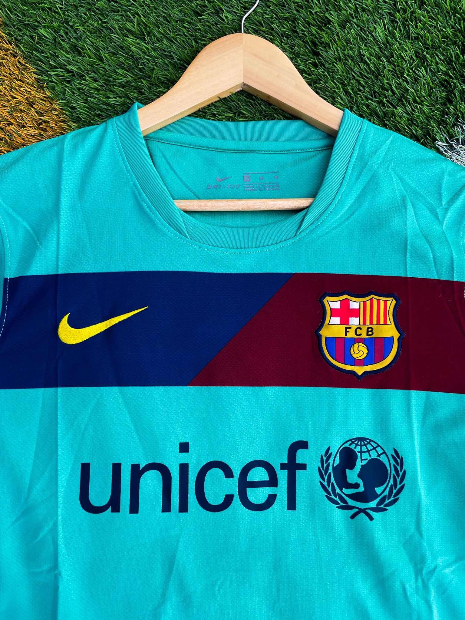 Close-up of Nike logo, Barça crest, and green gradient detail

