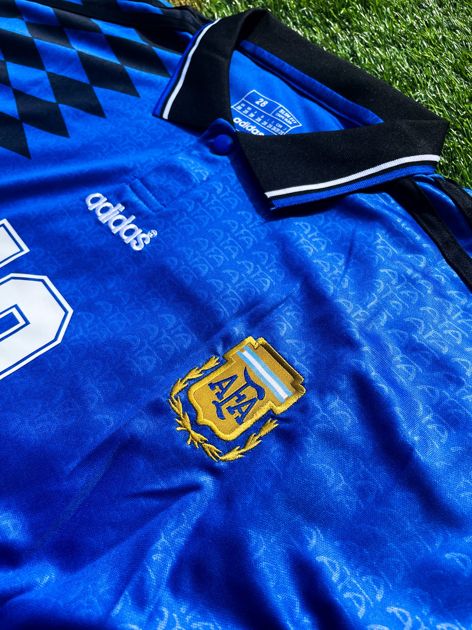 Close-up of the Adidas trefoil and classic collar on the kids’ vintage jersey.