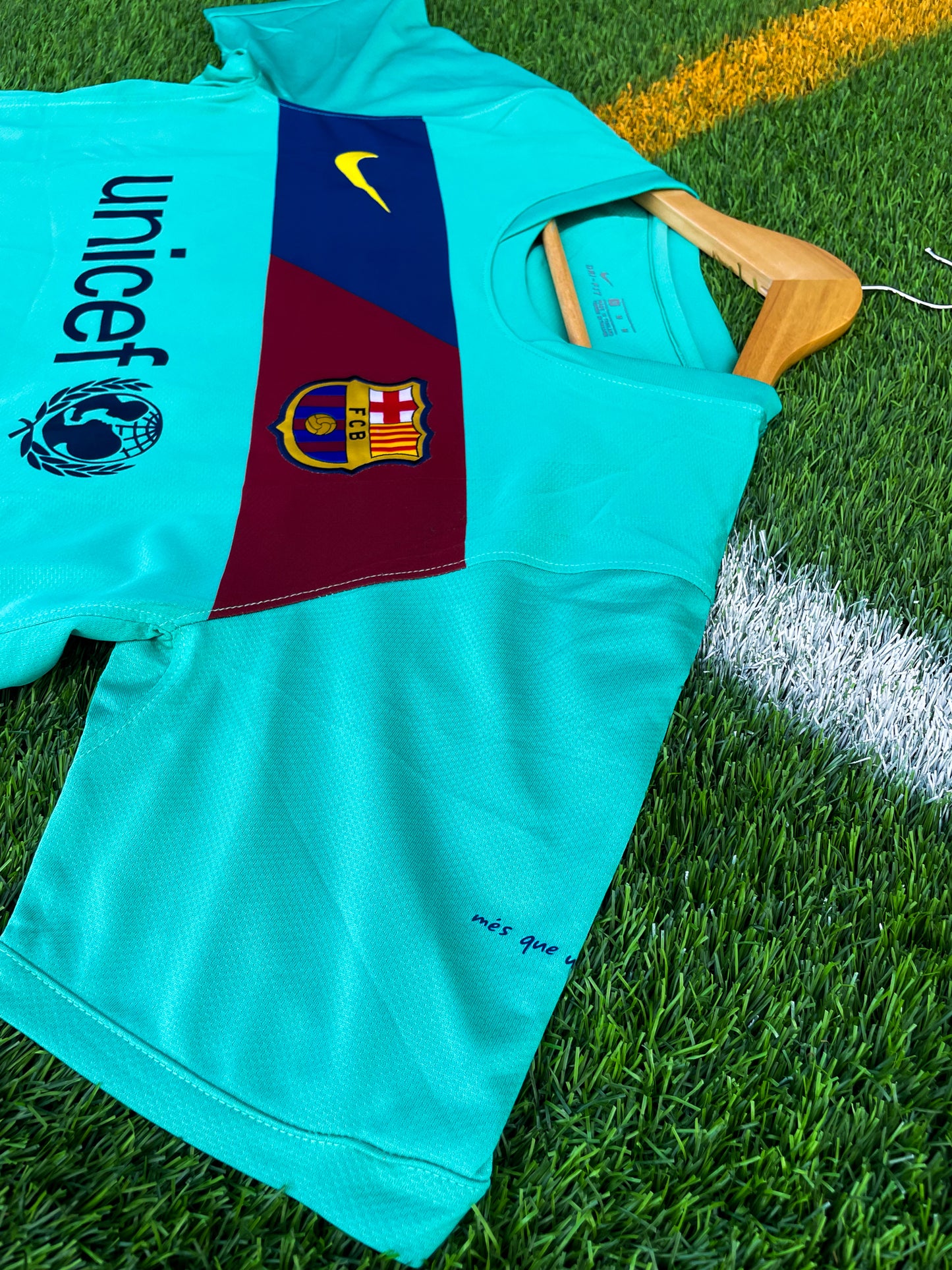 Close-up of Nike logo, Barça crest, and green gradient detail

