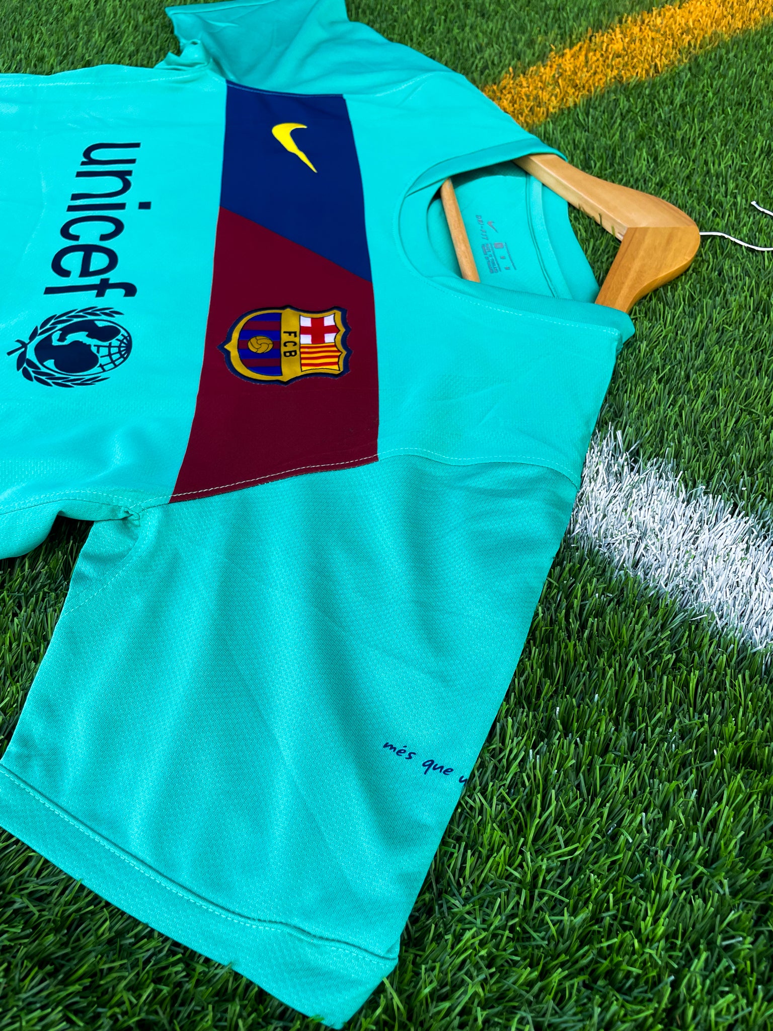 Close-up of Nike logo, Barça crest, and green gradient detail

