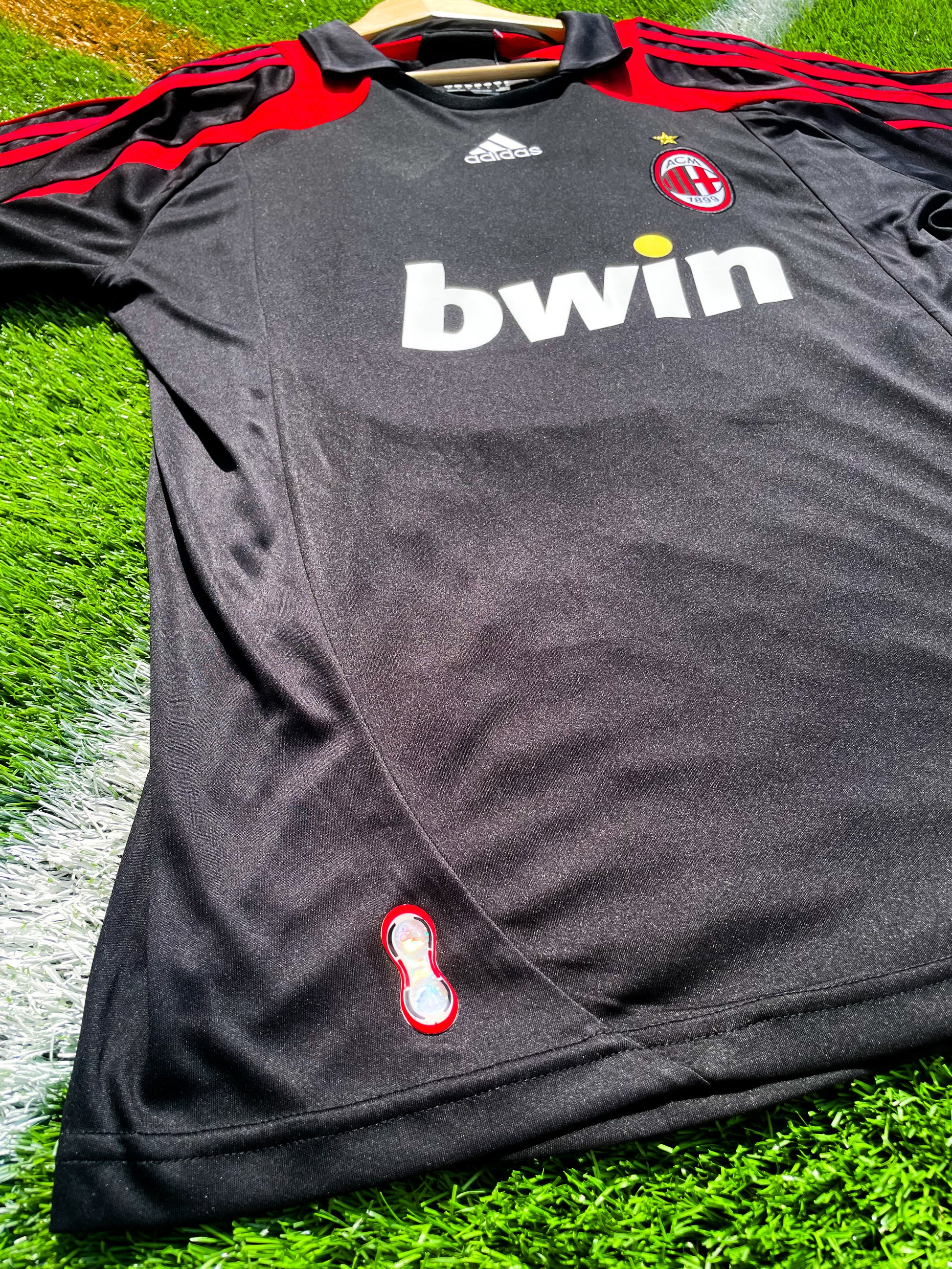 Close-up of AC Milan crest and Adidas logo on black fabric

