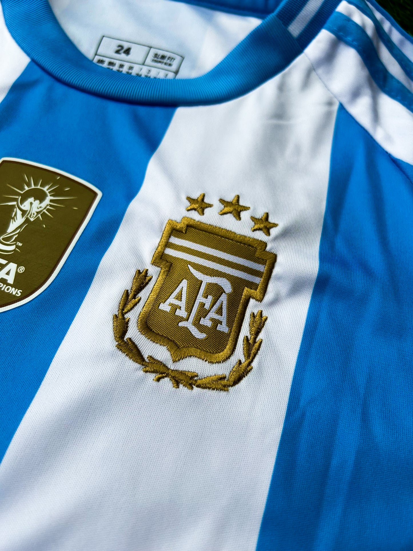 Close-up of Copa América champions badge and Adidas branding on youth jersey.