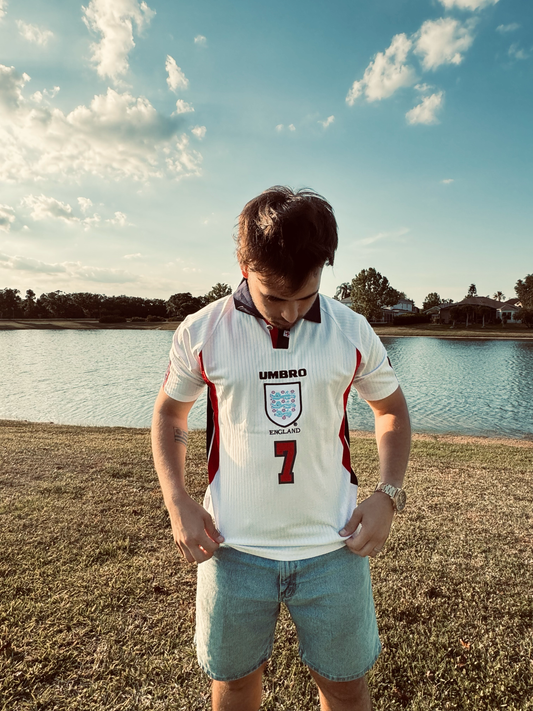 Styled photo of model wearing England 1998 retro jersey outdoors.

