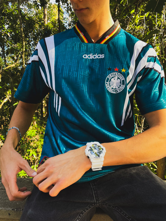 Model styling the Germany 1996 away jersey with retro football casualwear

