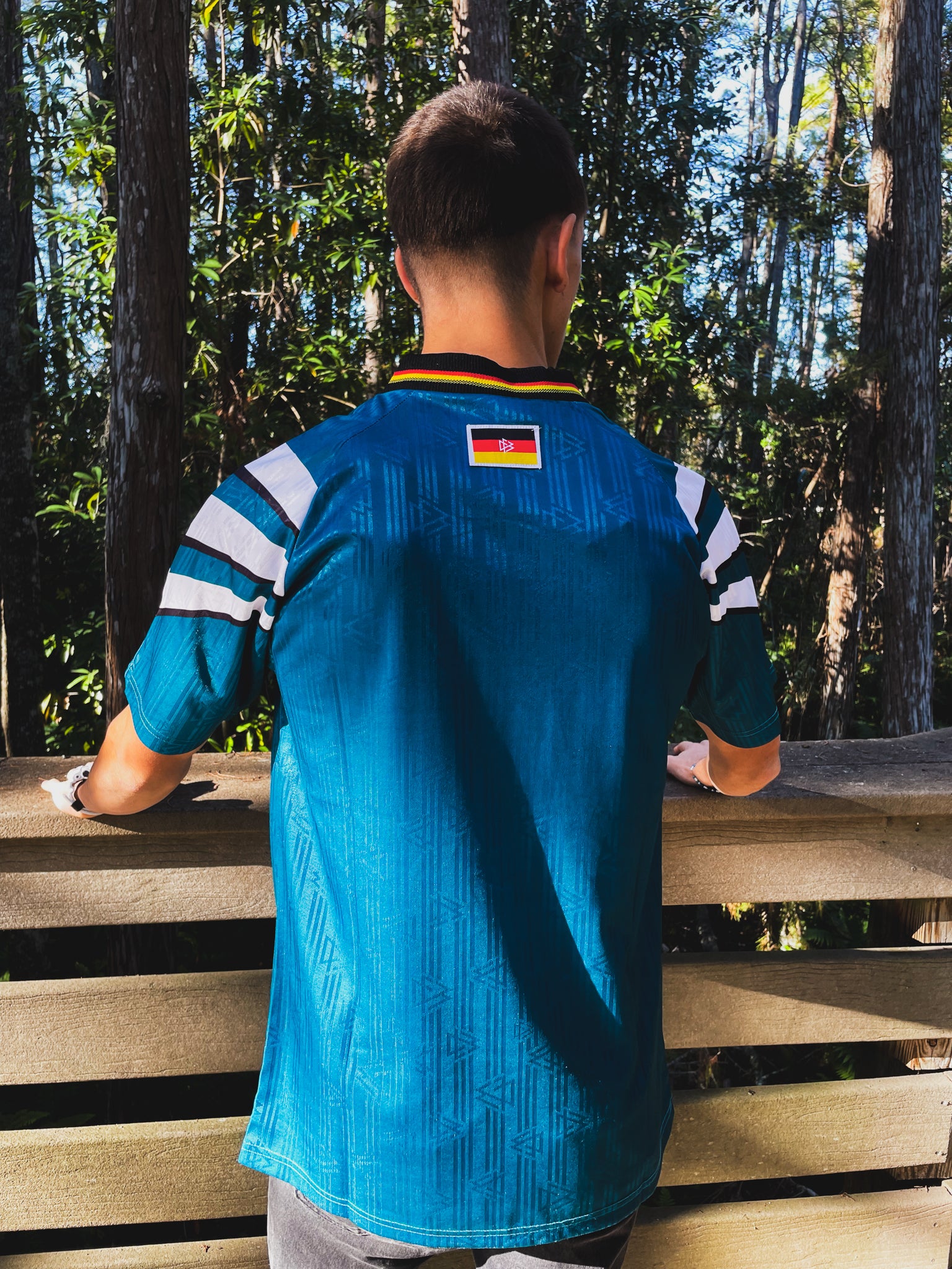 Model styling the Germany 1996 away jersey with retro football casualwear

