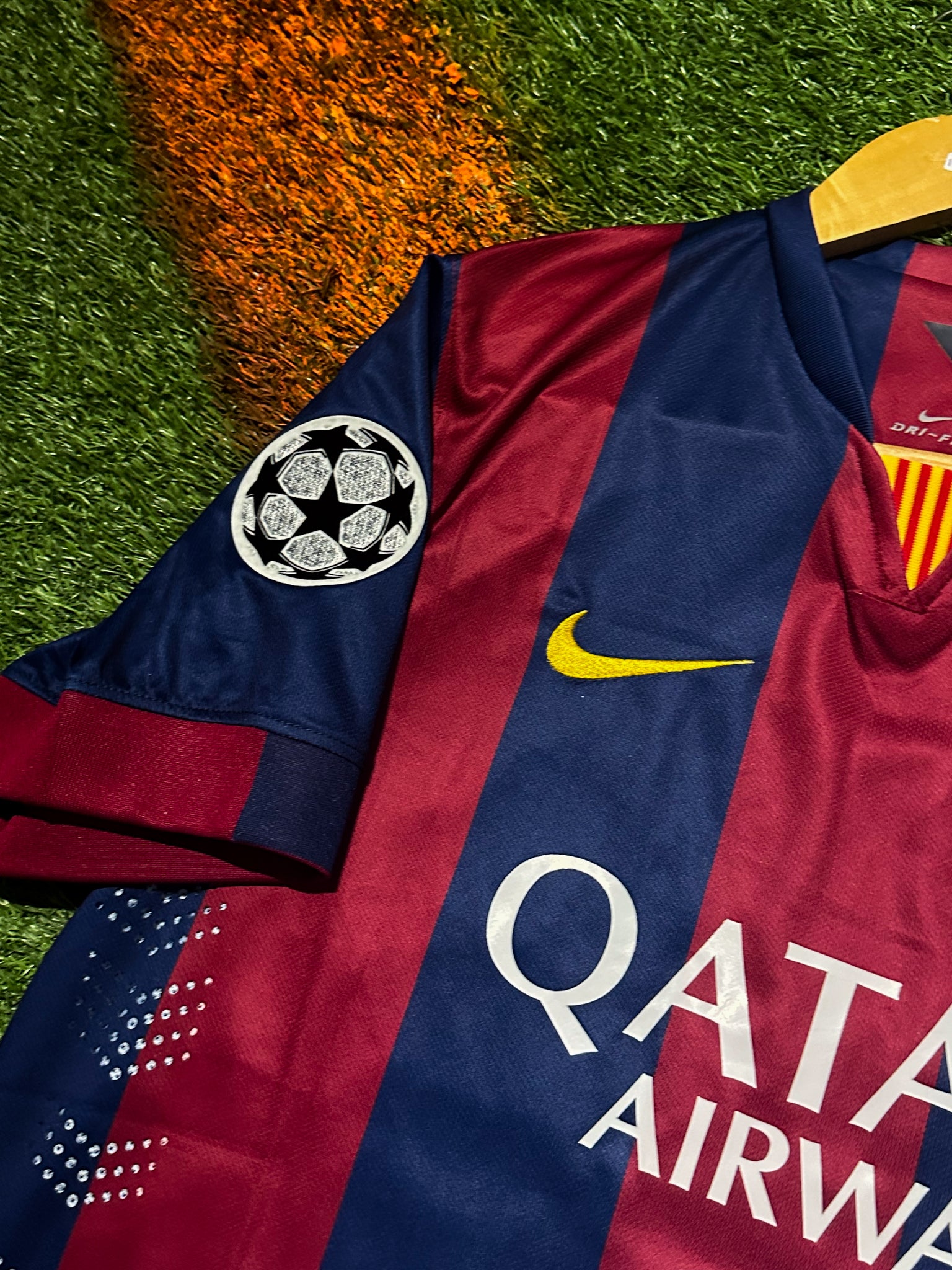 FC Barcelona 2014-15 home jersey with red and blue stripes, Nike logo, Qatar Airways sponsor, and Champions League patch.