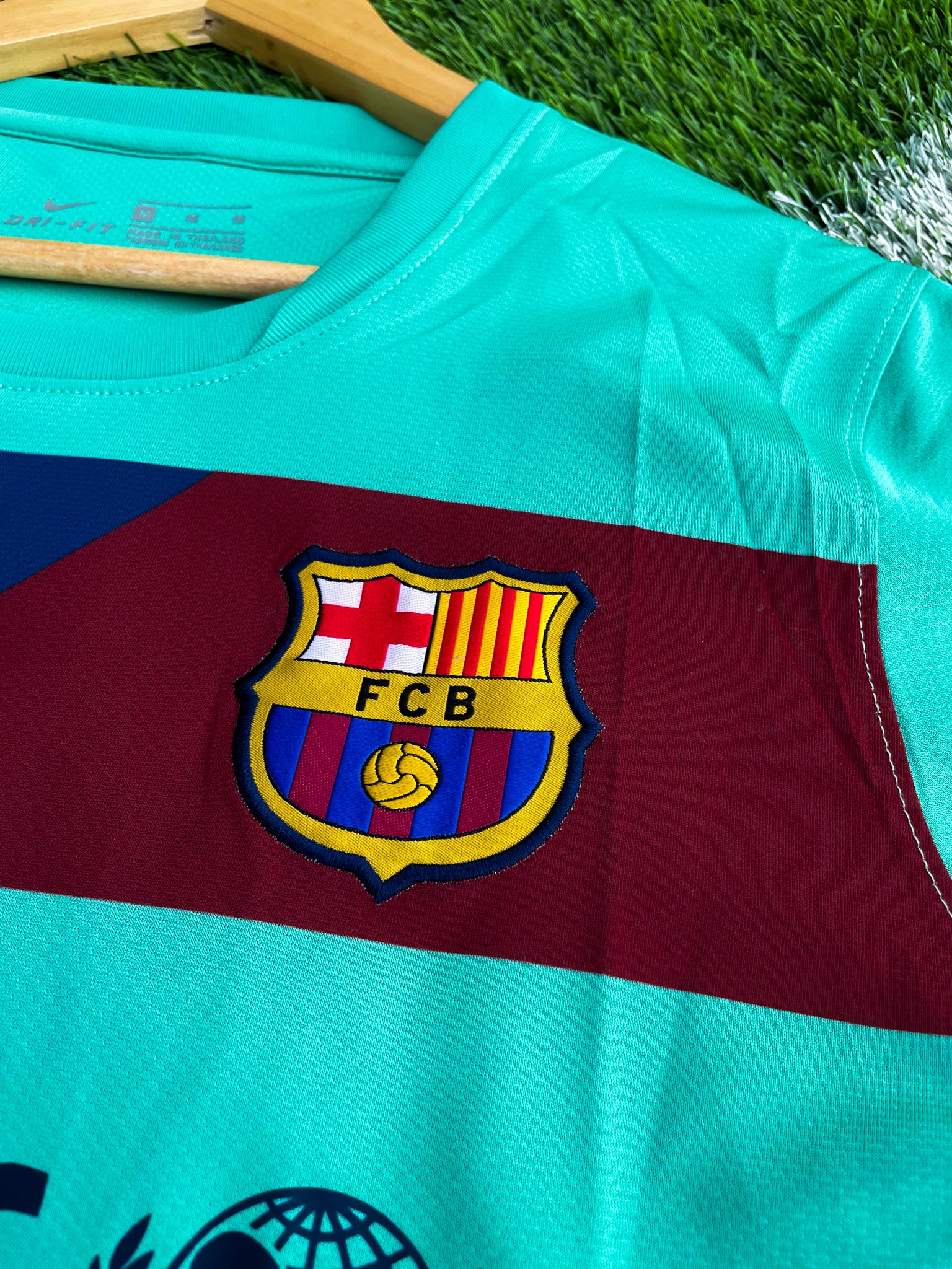 Close-up of Nike logo, Barça crest, and green gradient detail

