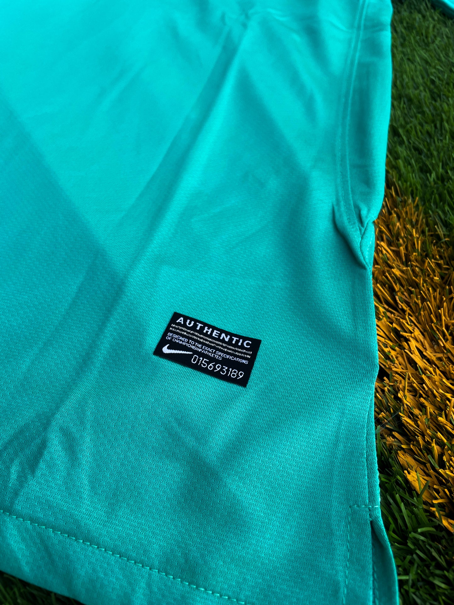 Close-up of Nike logo, Barça crest, and green gradient detail

