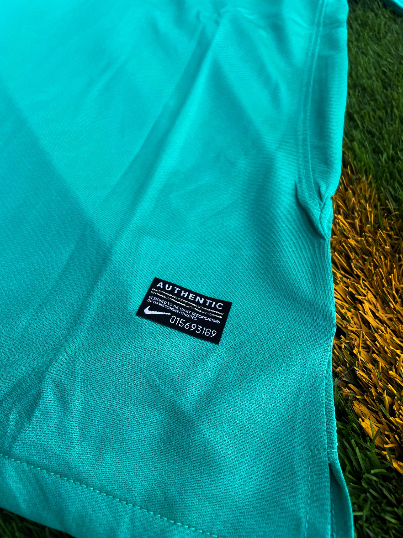 Close-up of Nike logo, Barça crest, and green gradient detail


