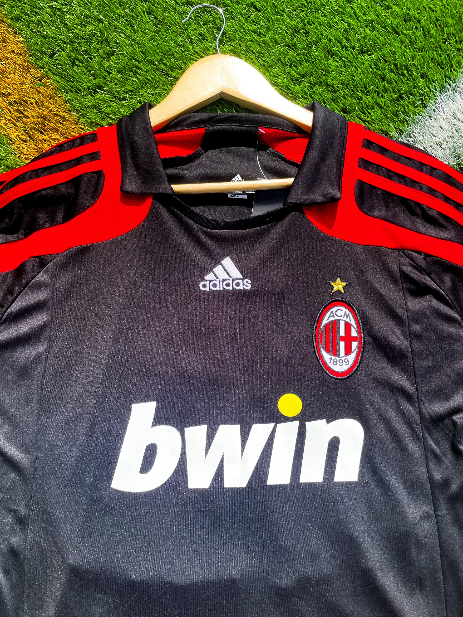 Close-up of AC Milan crest and Adidas logo on black fabric

