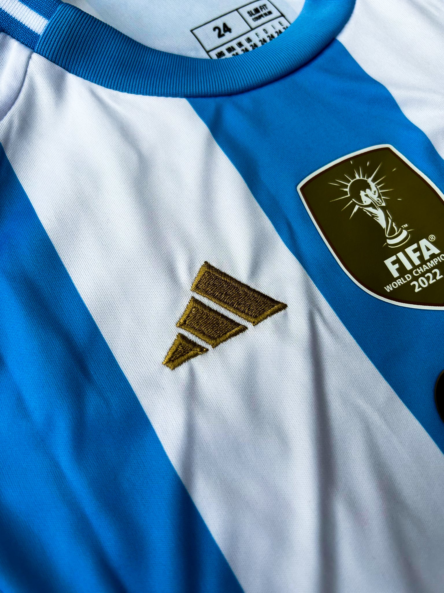 Close-up of Copa América champions badge and Adidas branding on youth jersey.