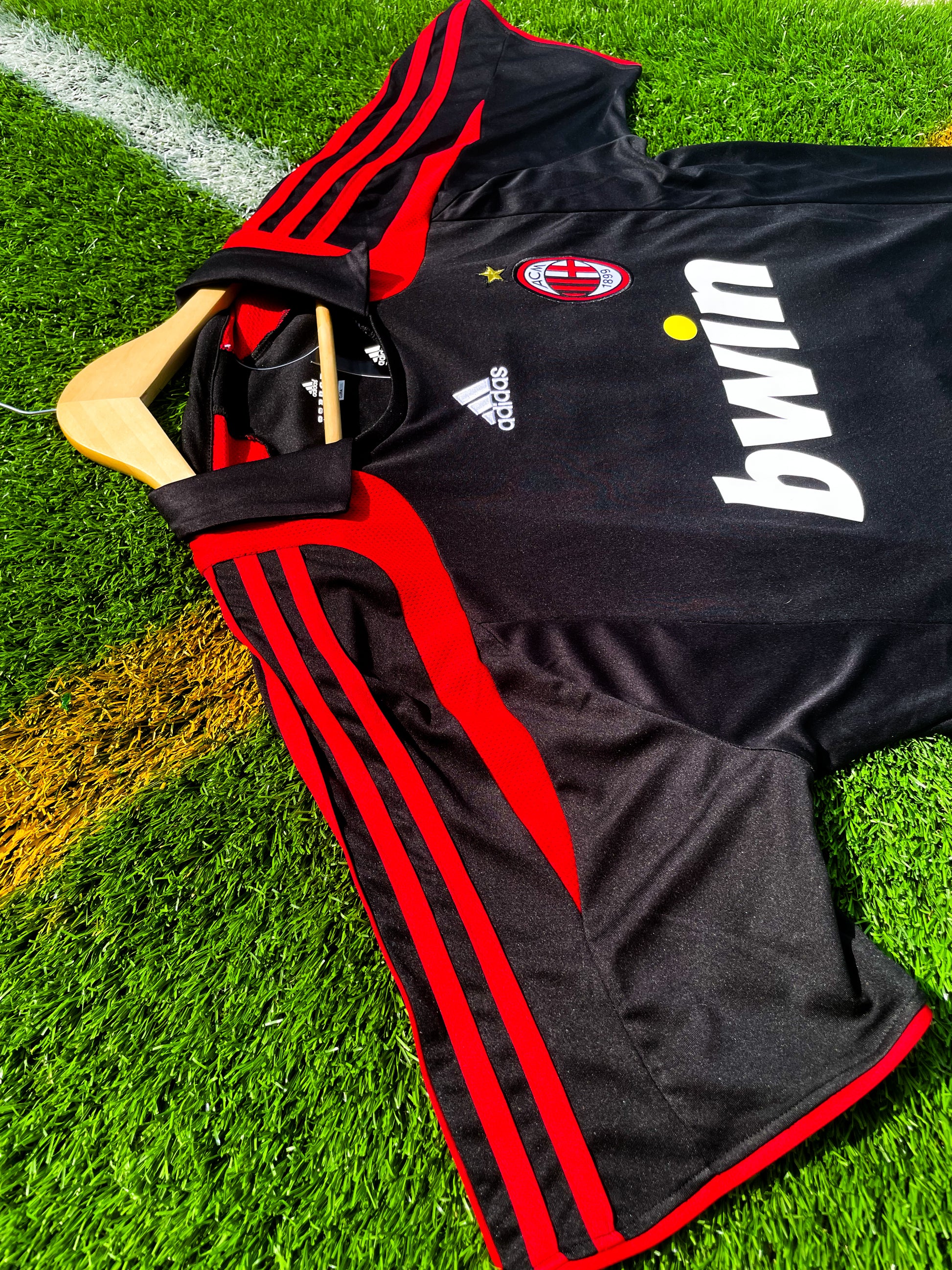 Close-up of AC Milan crest and Adidas logo on black fabric

