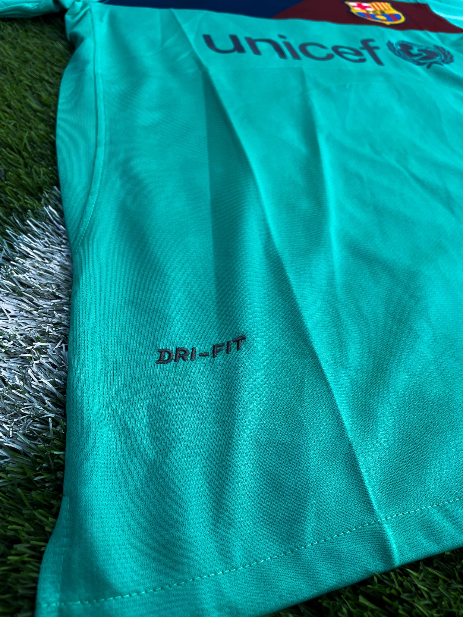 Close-up of Nike logo, Barça crest, and green gradient detail

